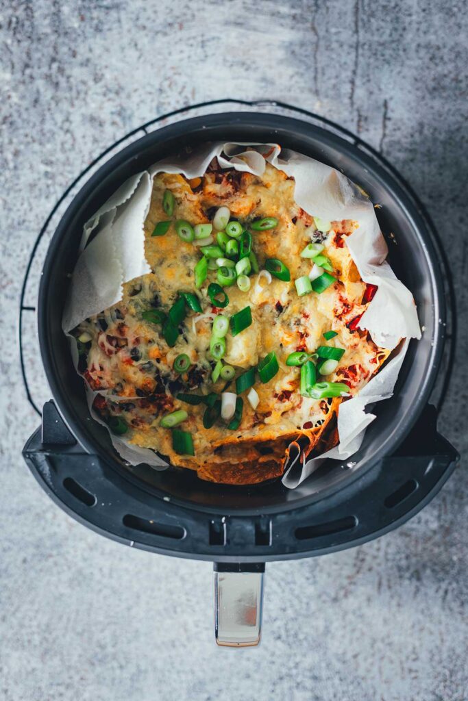 Loaded Nachos aus der Heißluftfritteuse sind eine blitzschnelle und unkomplizierte Idee für mit Käse und Toppings überbackene Tortilla Chips als Snack. Dafür werden alle Zutaten in den Airfryer geschichtet und zusammen gebacken. Anschließend kann man die Nachos mit Guacamole und Sour Cream servieren. | moeyskitchen.com